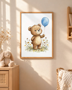 Gerahmtes Bärenposter mit blauem Luftballon an einer sonnigen Wand, daneben ein Holzschrank mit Stoffhasen, Trockenblumen und ein Korb mit Kissen.