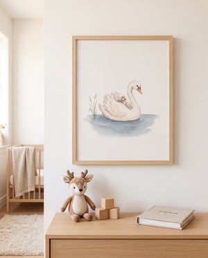 Schwan mit Küken als Poster im hellen Holzrahmen über einer Holzkommode mit Stoffreh, Holzklötzen und einem Buch. Links sind ein Kinderbett mit Decke und ein heller Teppich zu sehen.