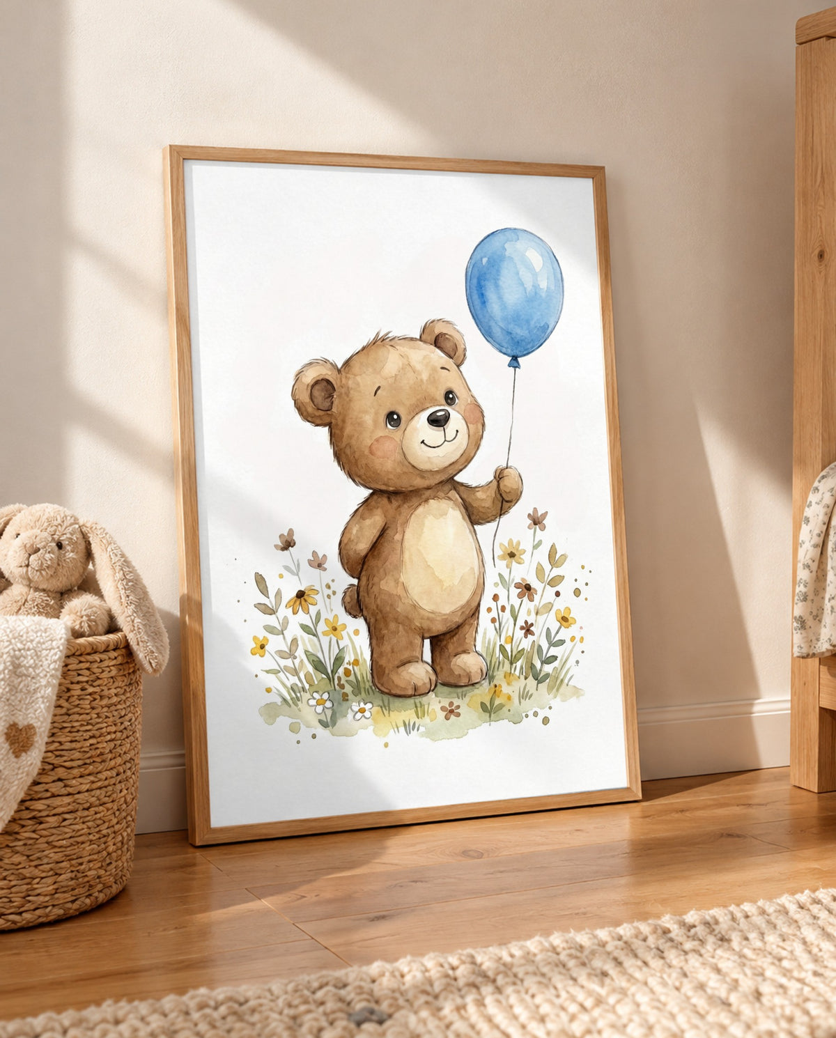 Großes Poster mit Bär, blauem Luftballon und Wiesenblumen im Holzrahmen, auf dem Holzboden an die Wand gelehnt, neben einem geflochtenen Korb mit Stoffhasen.