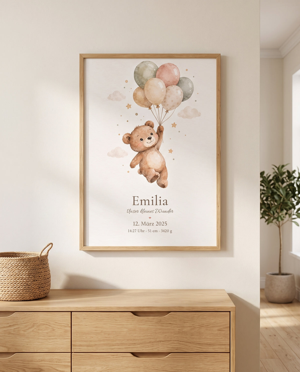 Gerahmtes Aquarellposter mit Bär und Luftballons über einer Holzkommode mit Flechtkorb; rechts ist eine grüne Pflanze in einem hellen Topf zu sehen.