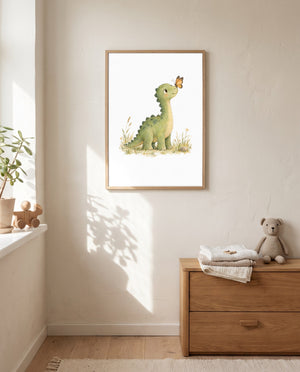 Gerahmtes Poster mit grünem Dinosaurier und Schmetterling an einer hellen Wand neben einem Fenster; darunter eine Holzkommode mit gefalteten Textilien und einem Stoffbären.