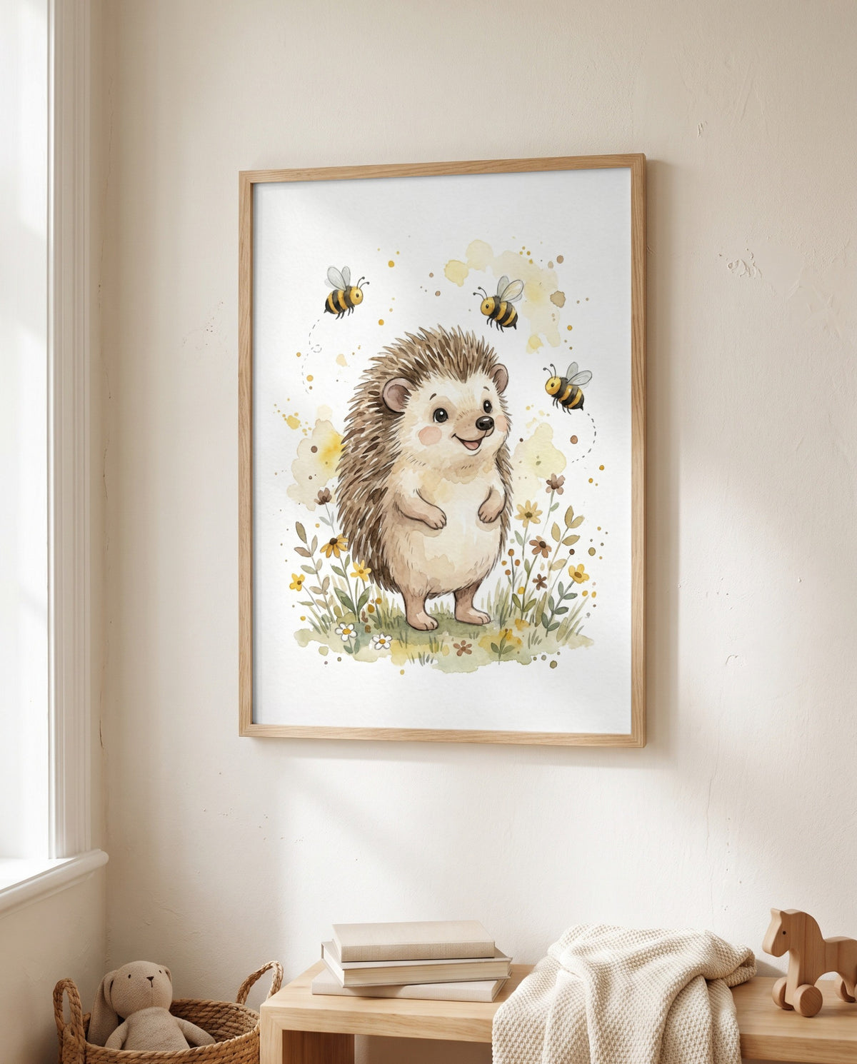 Gerahmtes Igel-und-Bienen-Poster neben einem Fenster, darunter eine Holzbank mit Büchern, heller Decke und Holzpferd sowie ein Korb mit Stofftier.