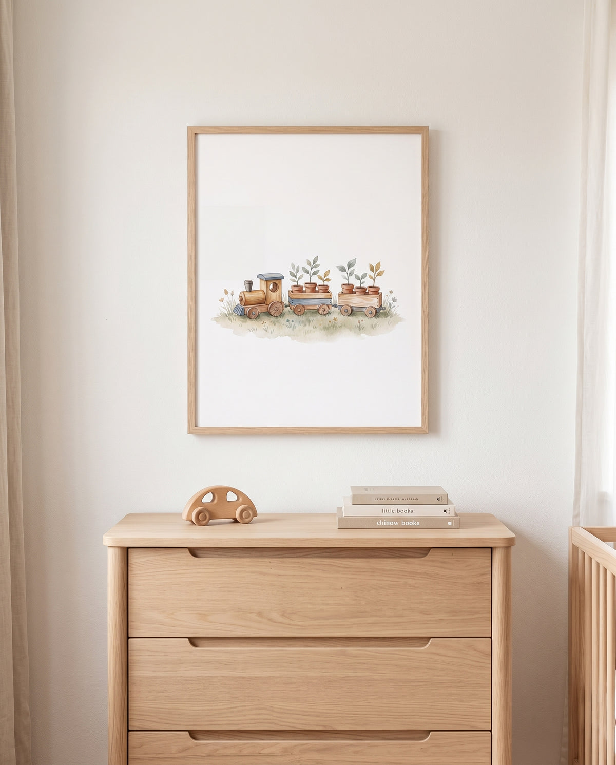 Eisenbahn-Poster im Holzrahmen über einer Kommode mit Holzauto und Büchern in einem hellen Kinderzimmer