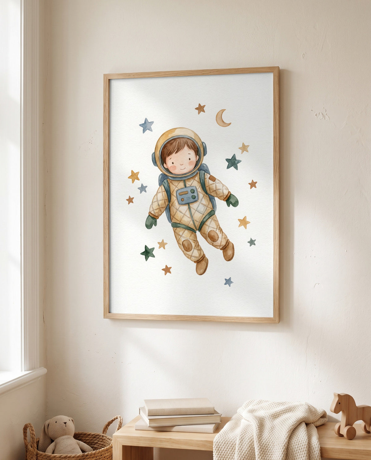 Astronautenposter mit Sternen und Mondsichel im Holzrahmen neben einem Fenster. Darunter stehen Bücher, eine Strickdecke und ein Holzpferd auf einem Holzmöbel; links sitzt ein Stofftier in einem Korb.