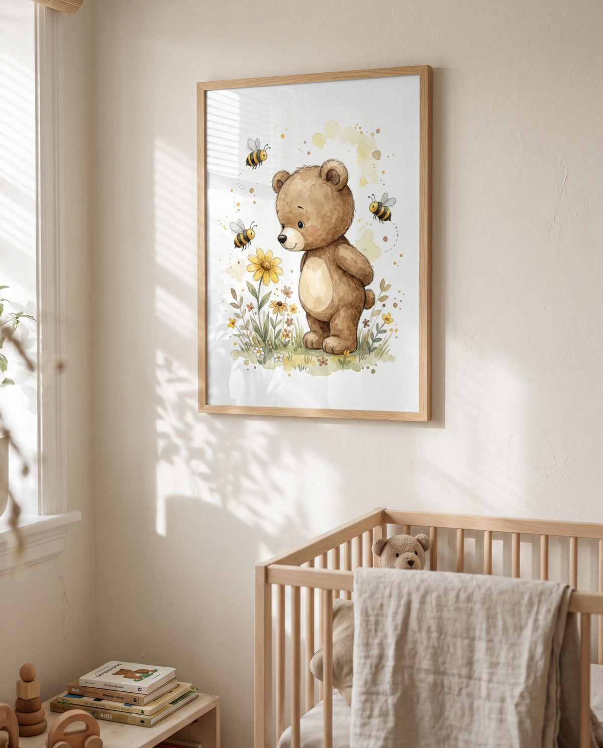Gerahmtes Bär-und-Bienen-Poster über einem Holz-Gitterbett mit Stoffteddy und über dem Gitter hängendem Tuch; links ein Fenster und ein niedriger Tisch mit Büchern und Holzspielzeug.