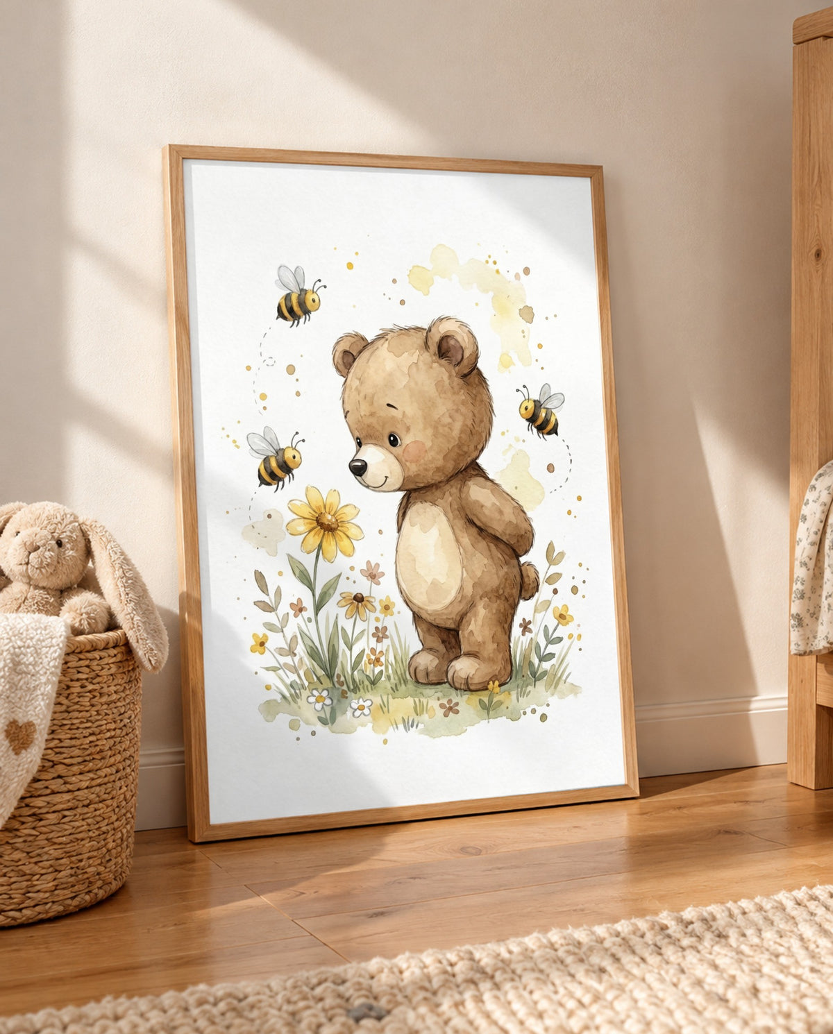 Großes Bär-und-Bienen-Poster im Holzrahmen, auf einem Holzboden an die Wand gelehnt; daneben ein geflochtener Korb mit Stoffhase und Decke, rechts ein Holzmöbel und vorne ein heller Teppich.