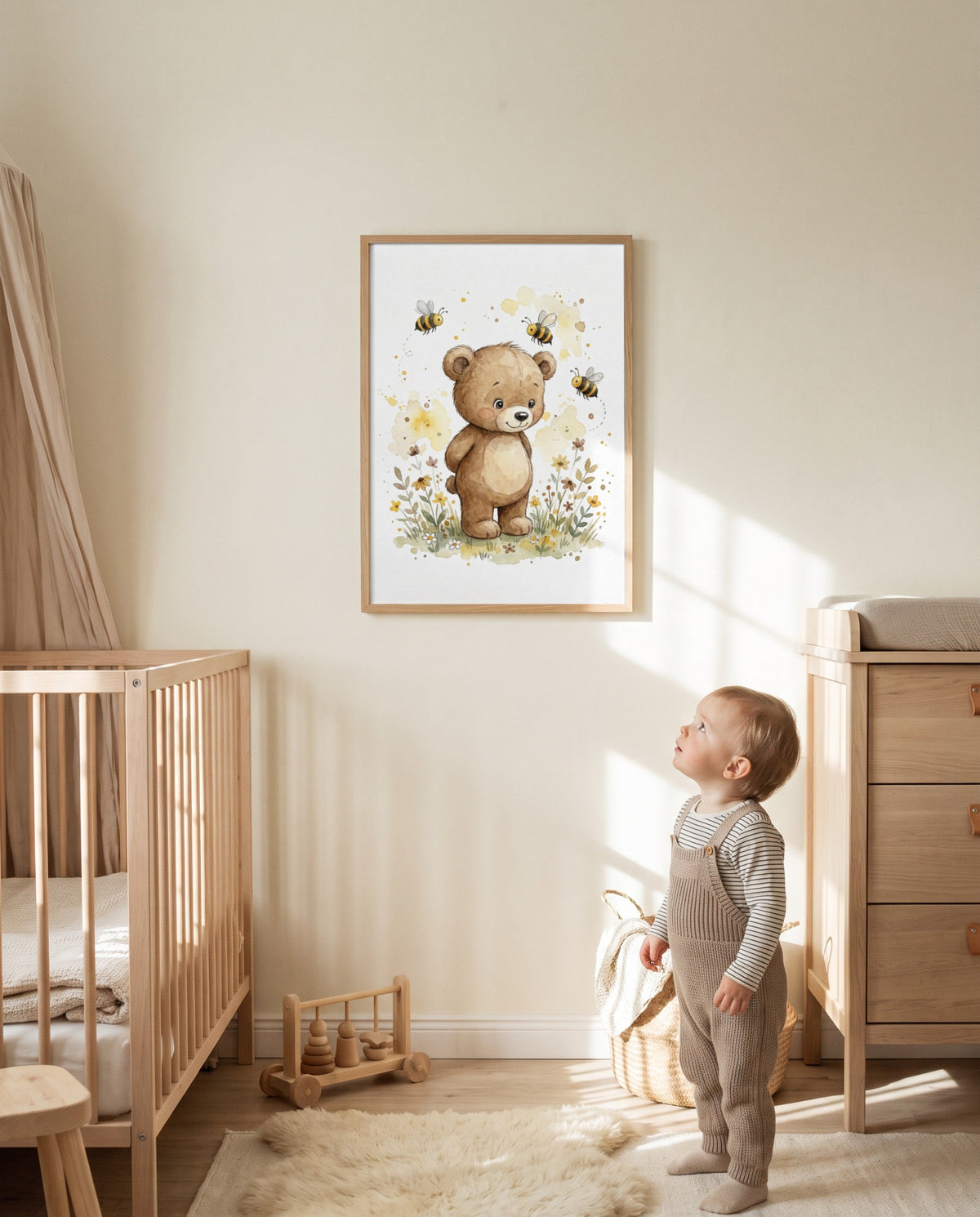 Bärenposter mit Bienen im Holzrahmen an der Kinderzimmerwand zwischen Gitterbett und Wickelkommode; ein Kleinkind steht darunter neben einem Korb und Holzspielzeug.