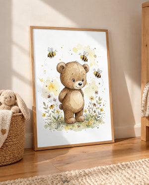 Großes gerahmtes Poster mit braunem Bären, drei Bienen und Wiesenblumen, auf dem Holzboden an die Wand gelehnt; daneben ein geflochtener Korb mit Stoffhasen und Decke.