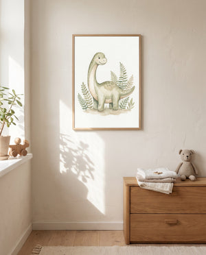 Langhals-Dino-Poster im hellen Holzrahmen an einer sonnenbeschienenen Wand über einer Holzkommode mit gefalteten Textilien und Stoffbär; am Fenster stehen eine Pflanze und ein Holzspielzeug.