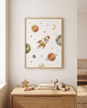 Raketenposter im hellen Holzrahmen über einem niedrigen Holzschrank mit Holzstern, Greifling, gestapelten Büchern und gestricktem Kuscheltier; rechts ist ein Gitterbett sichtbar.